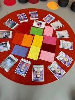 Frida-Kahlo-Projekts eine rote kreisförmige matte mit bunten, strukturierten karten und mehreren karten mit abbildungen von frida kahlo, die in einem kreis auf einem grauen boden angeordnet sind.